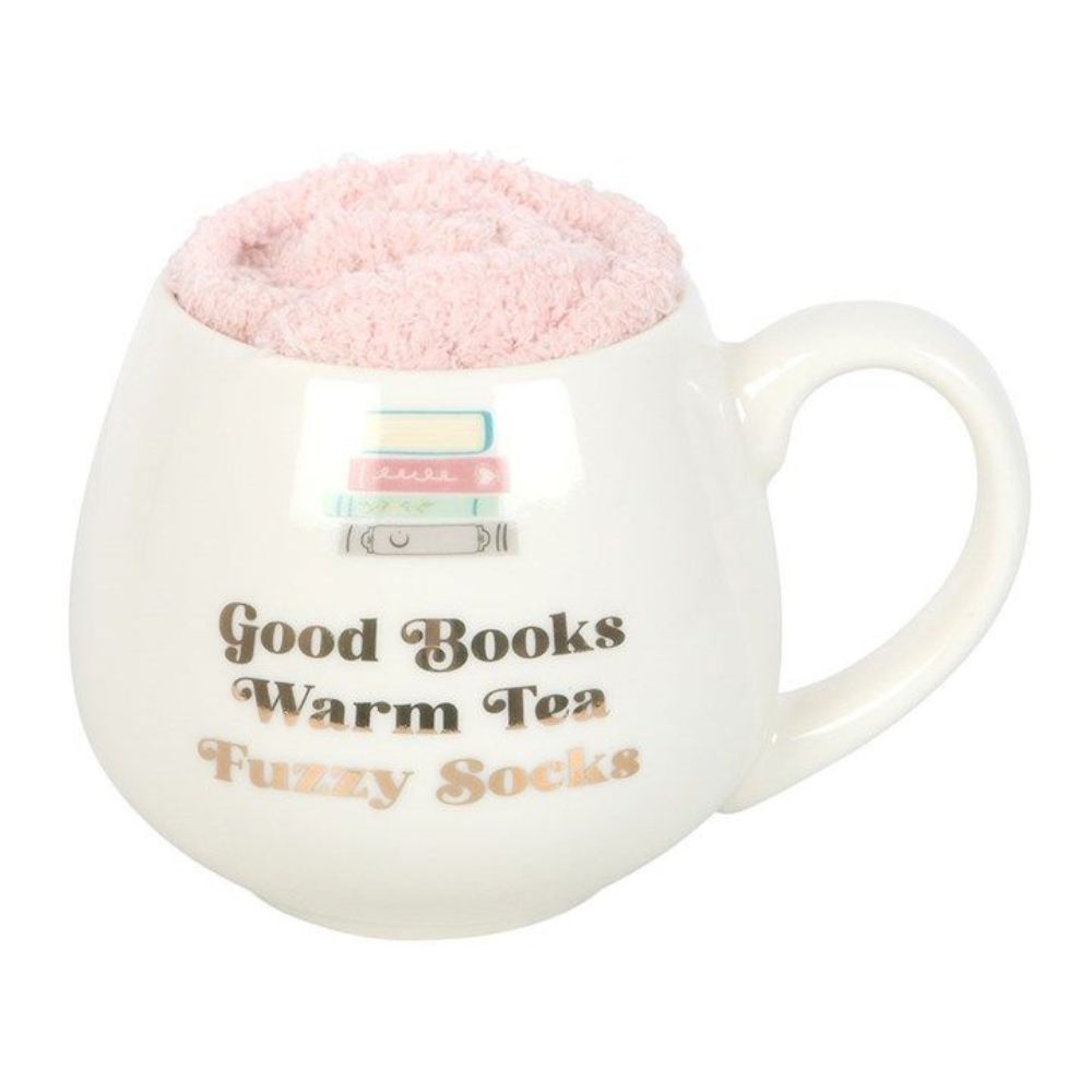 White mug with pink fluffy interior, text 'Good Books Warm Tea Fuzzy Socks', and a small stack of books on a white background.