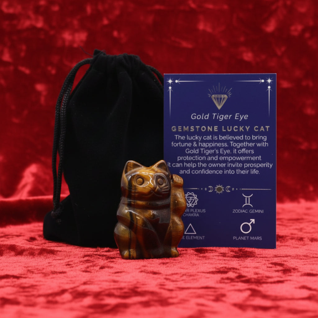 A hand-carved purple gemstone in the shape of a lucky cat, accompanied by a black velvet pouch and a card with details about the gemstone.