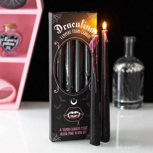 Black candles with pink interior in a decorative box labeled 'Draculina Vampire Tears Candles' on a white surface.