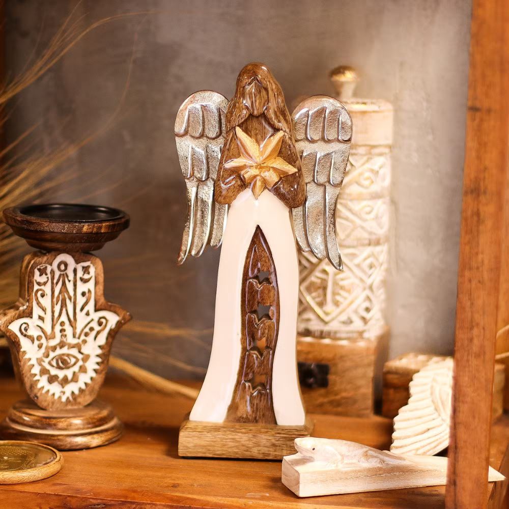 Decorative angel figurine with star on a wooden surface with other decorative items.