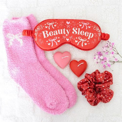 Pink and red sleep mask, socks, heart-shaped items, and a scrunchie on a white background