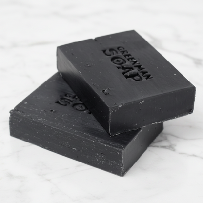 Two bars of black soap stacked on a white background with 'Greenman Soap' branding.