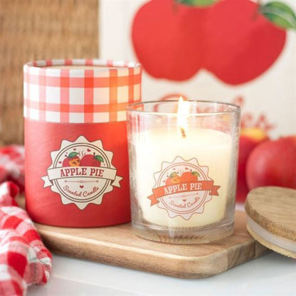 Apple pie scented candle with a red checkered lid on a wooden tray, surrounded by apple-themed decor.
