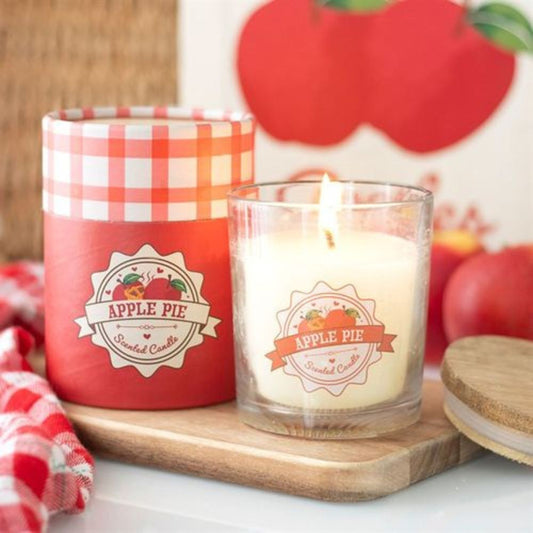 Apple pie scented candle with a red checkered lid on a wooden tray, surrounded by apple-themed decor.