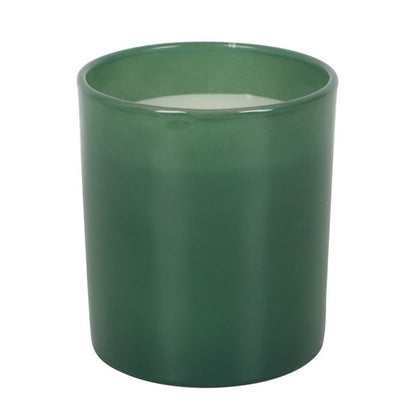 Green candle in a cylindrical container on a white background