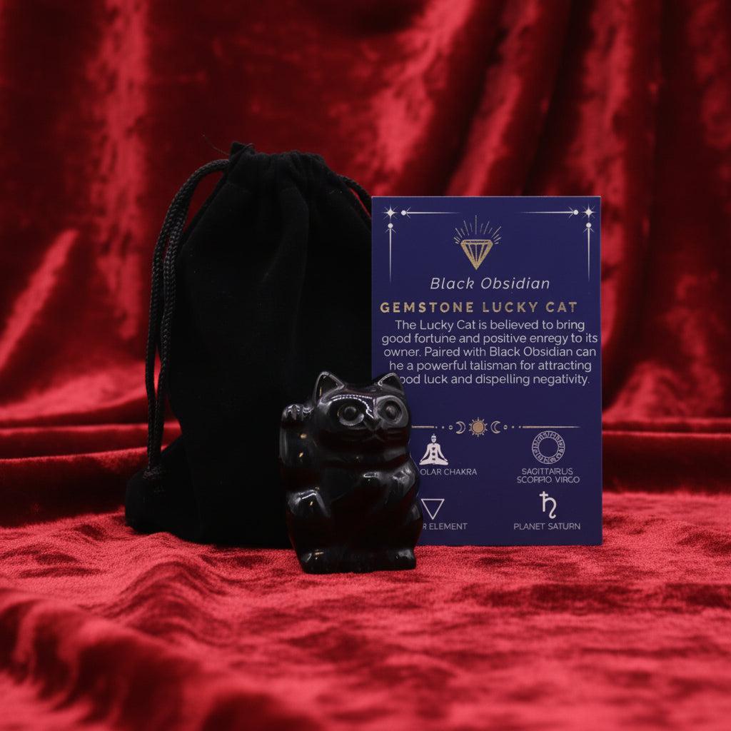 A hand-carved purple gemstone in the shape of a lucky cat, accompanied by a black velvet pouch and a card with details about the gemstone.