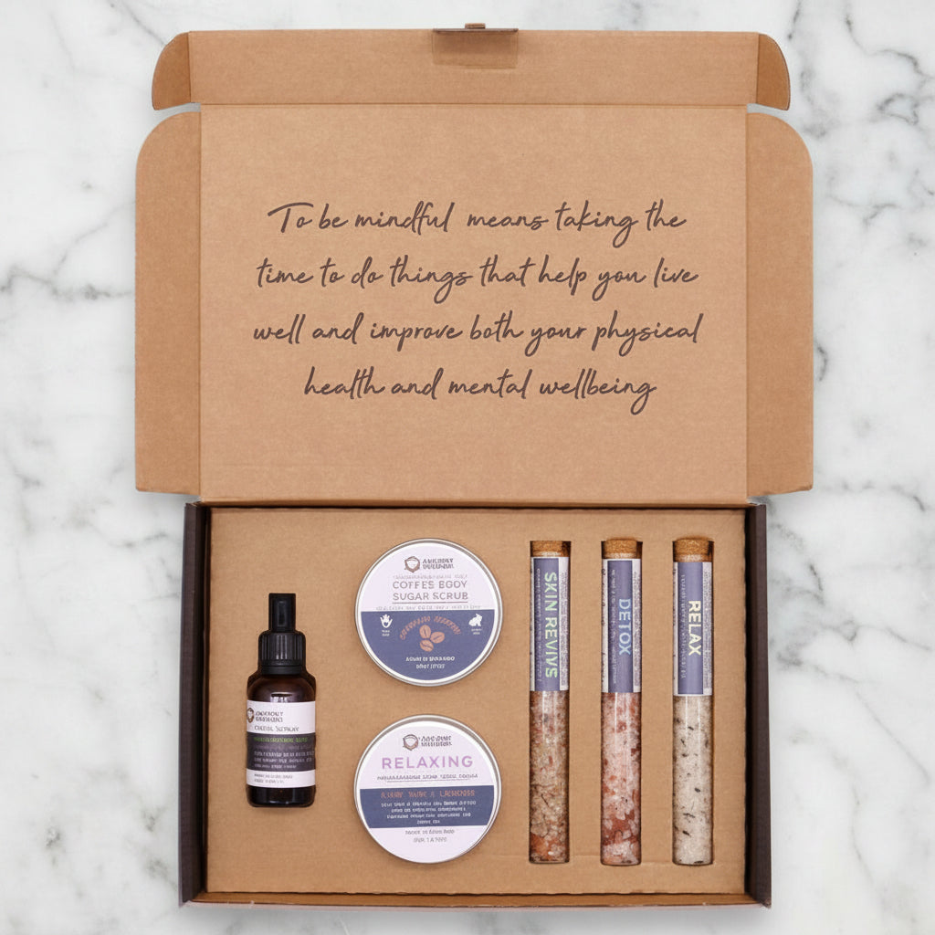 A self-care gift set box containing various bath products including a bottle, possibly of essential oil or perfume, and tubes with scrub and lotion.
